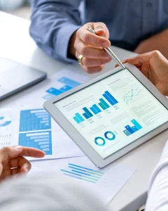 Close up of three people looking at financial data with graphs and charts.